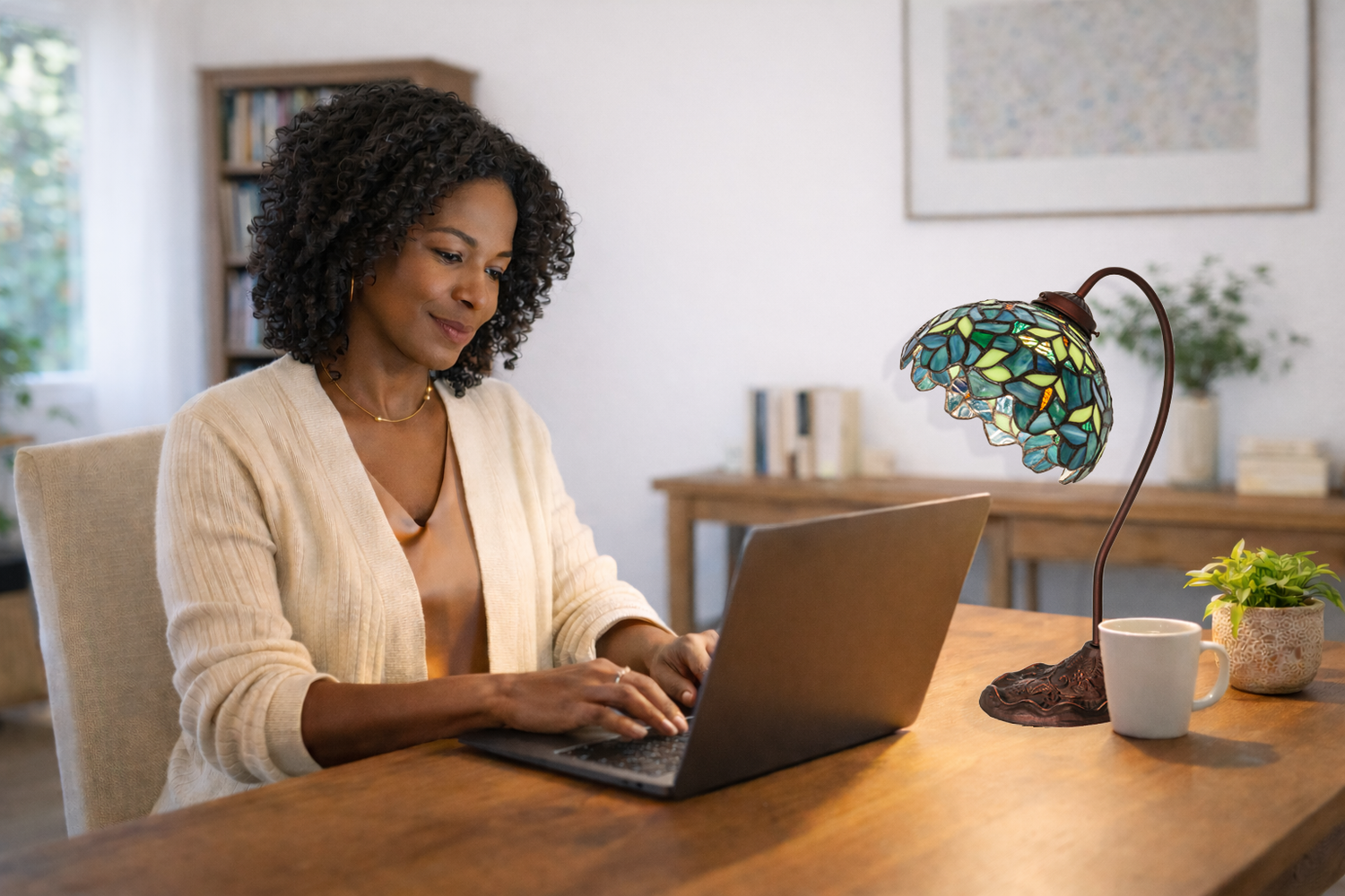 Tiffany nightfall wisteria desk lamp sitting on home desk. Woman working at computer. 